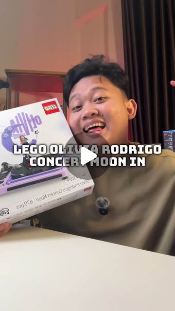 Adit smiling while holding the LEGO Olivia Rodrigo Concert Moon set in his studio